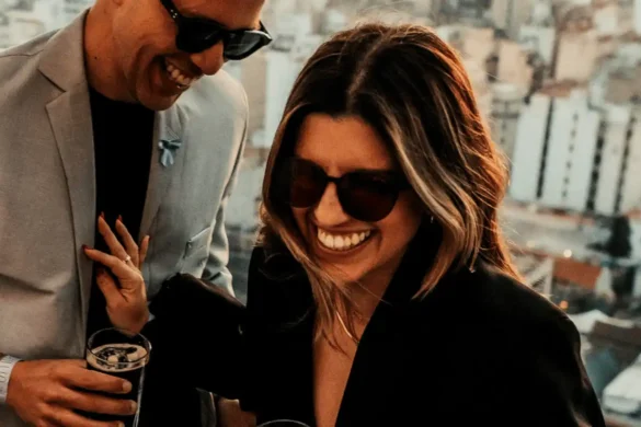 A woman and man are having a fun conversation. They both are laughing. The woman playfully pushes him away.