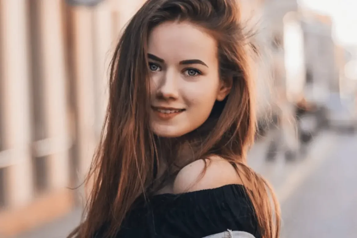 Young woman standing outside in the city smiling directly into the camera.