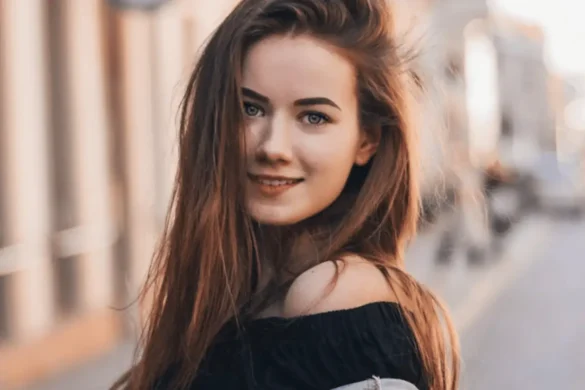 Young woman standing outside in the city smiling directly into the camera.