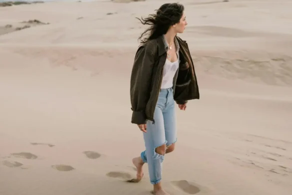 Young walking barefoot through the dessert sand, appearing deep in thought.