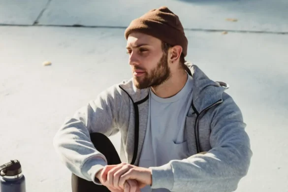 Man outdoor sitting on ground in deep thought.