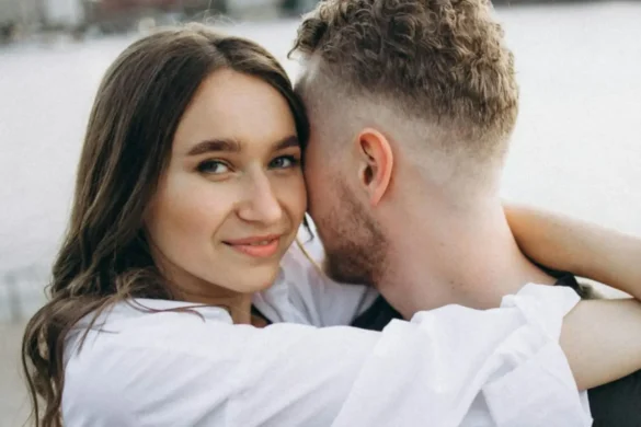 Young woman hugging a guy and smiling into the camera.