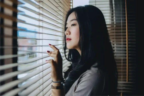 Young woman looking out window, looking deep in thought.