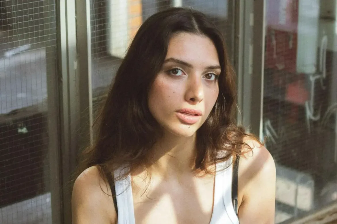 Young woman with her head tilted, looking into the camera.