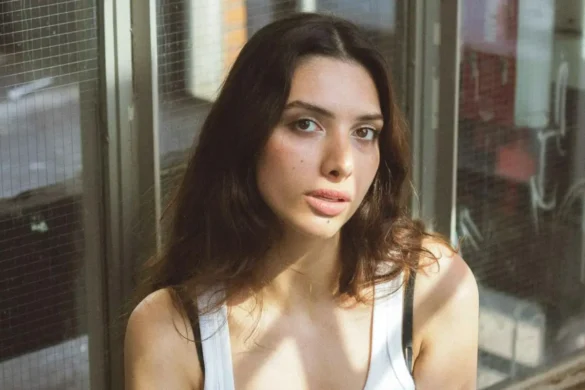 Young woman with her head tilted, looking into the camera.