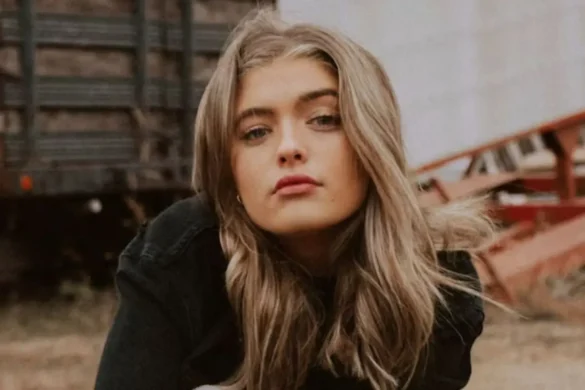 Young woman with long blonde hair outdoors, with a sassy expression.
