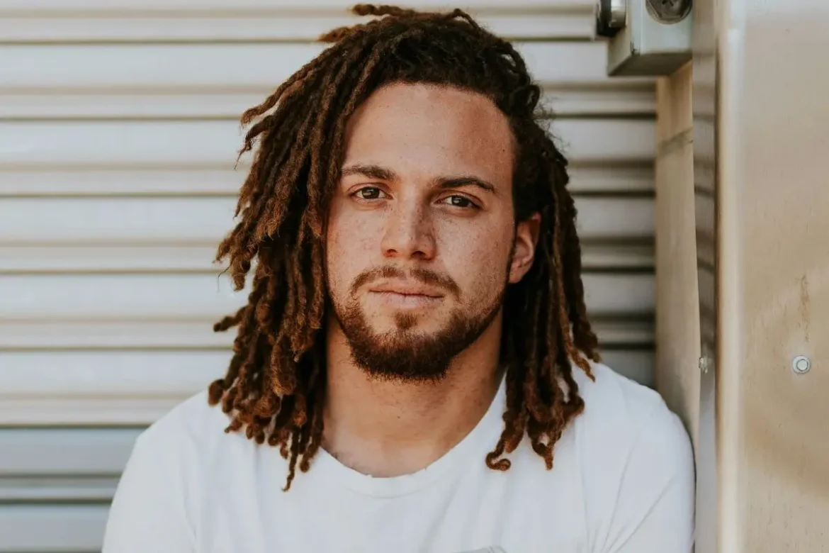 Guy with dreadlocks looking into the camera.