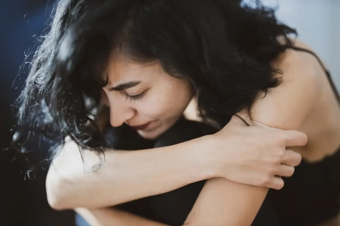 Woman's arm are around herself while crying